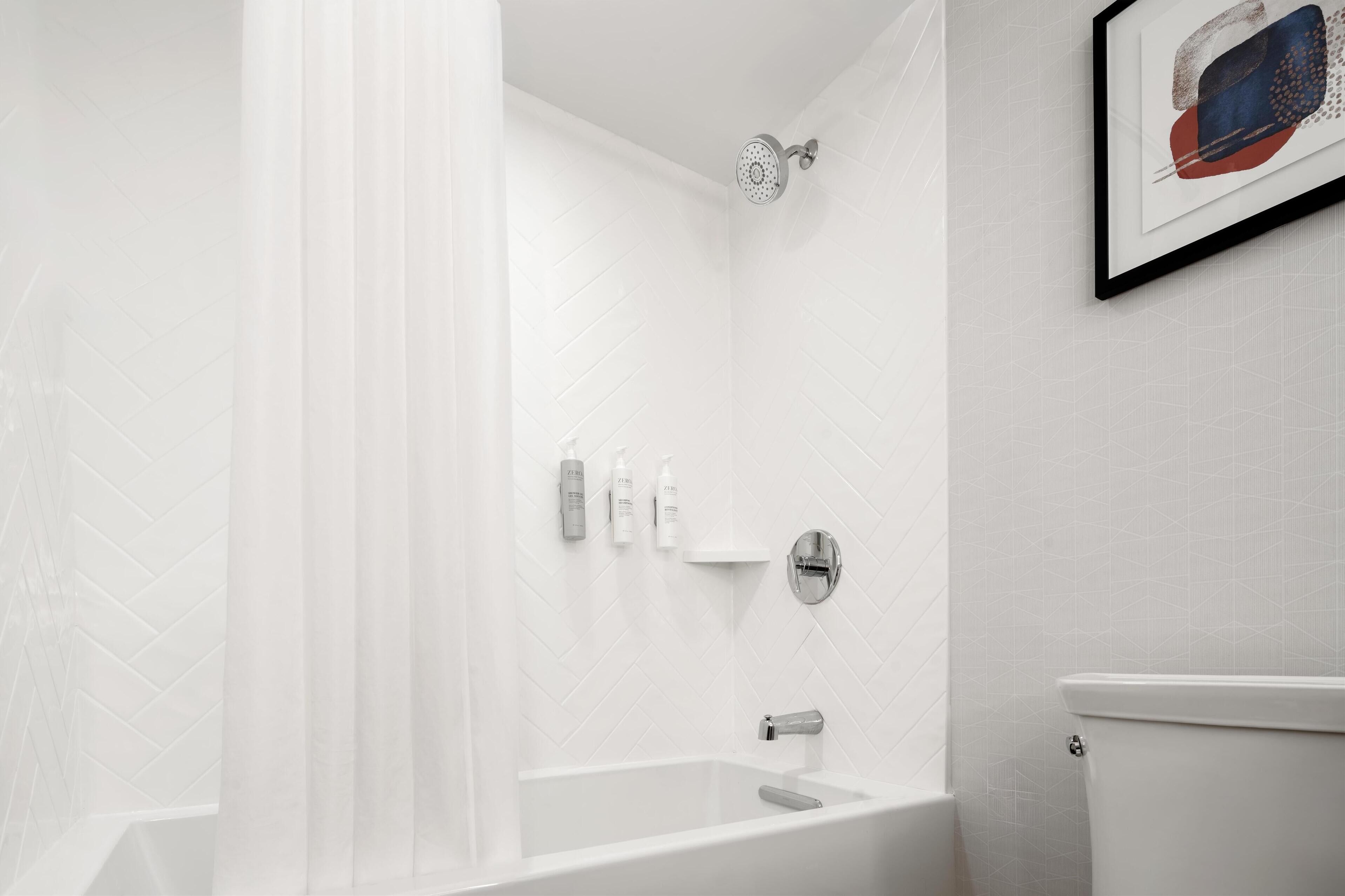 Un baño moderno con ducha, inodoro y una obra de arte enmarcada en la pared.