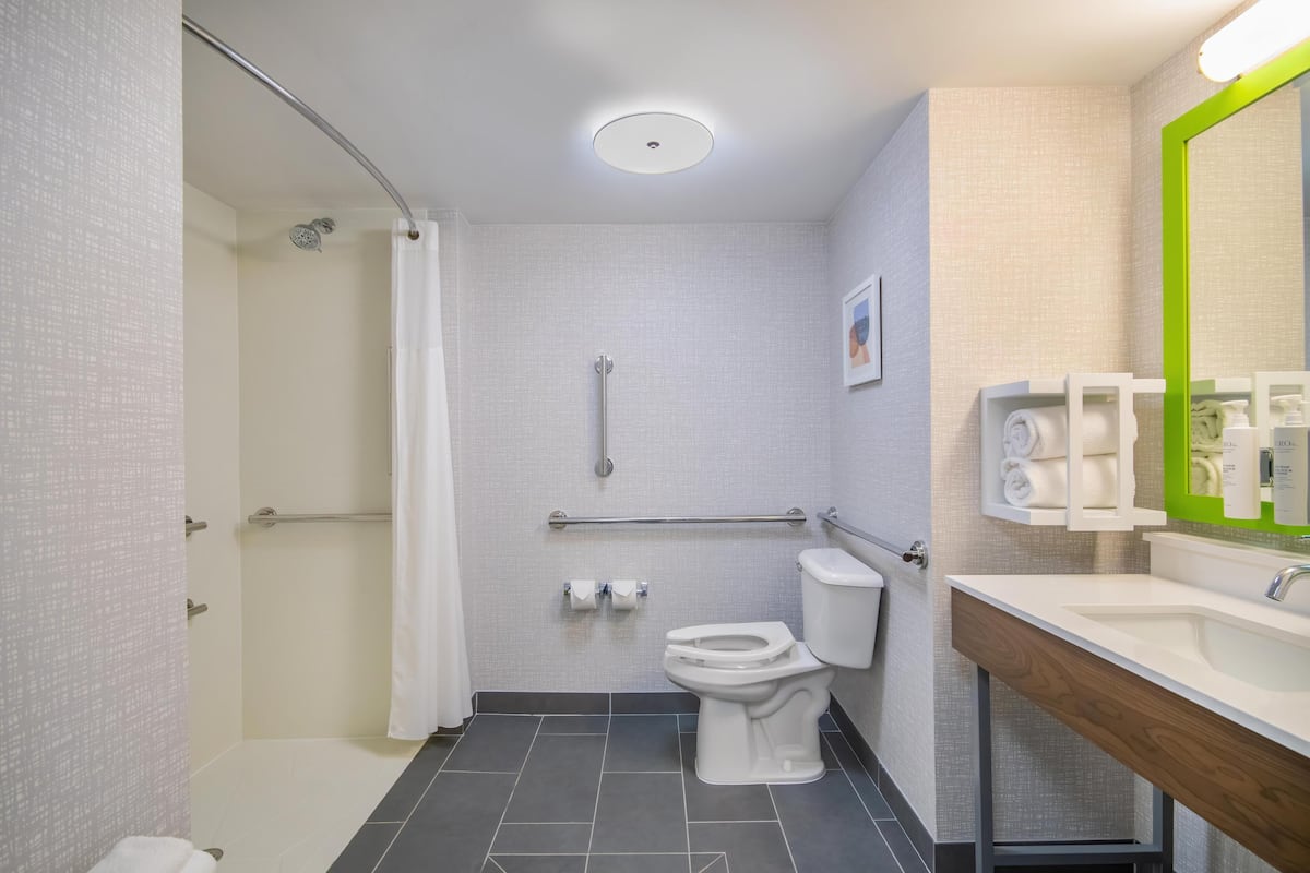 A modern bathroom with a shower, toilet, and sink.