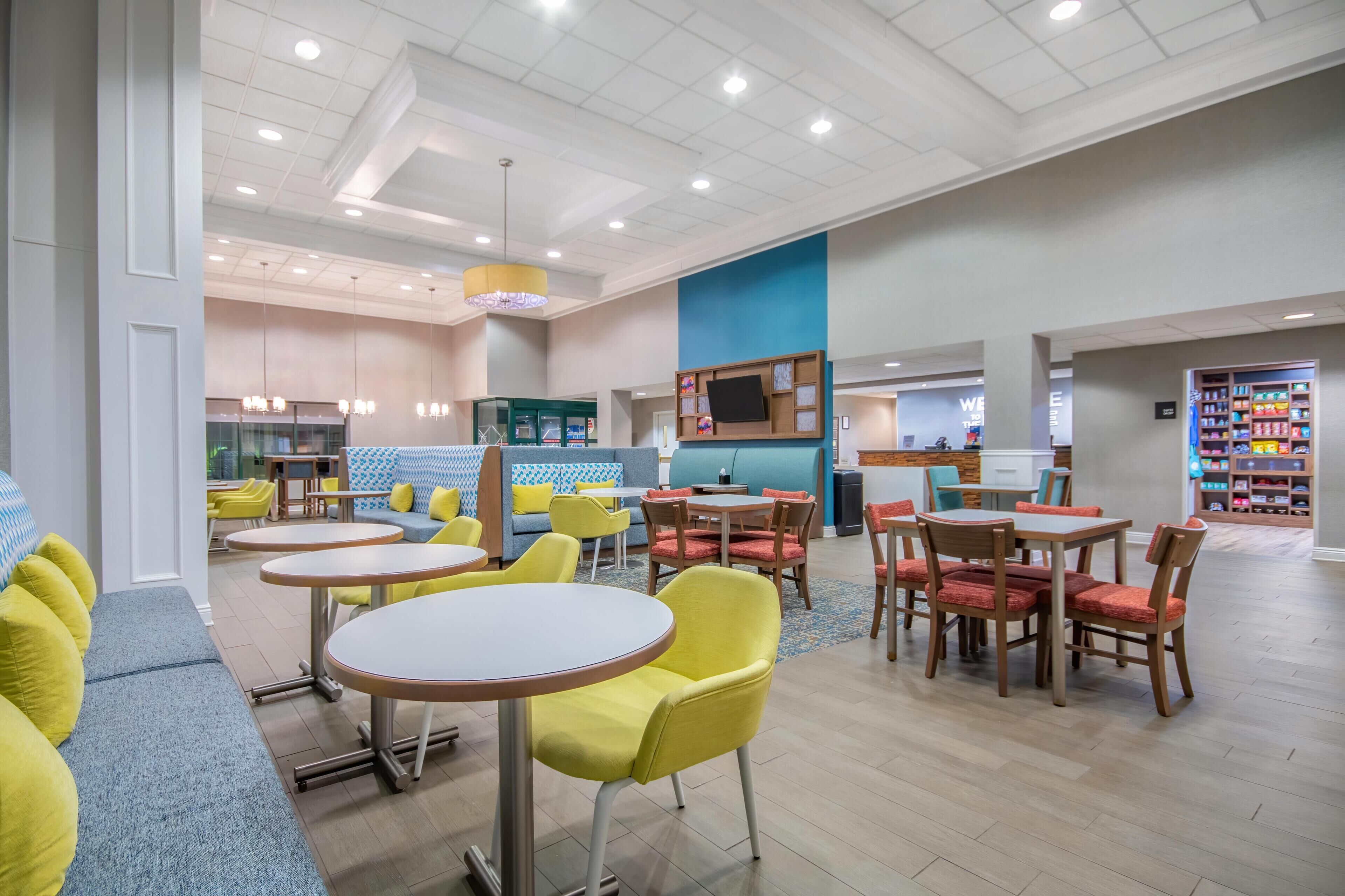 A modern interior with round tables, yellow chairs, and a blue accent wall.