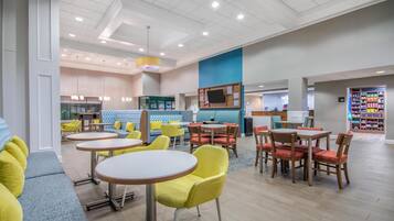 A modern interior with round tables, yellow chairs, and a blue accent wall.