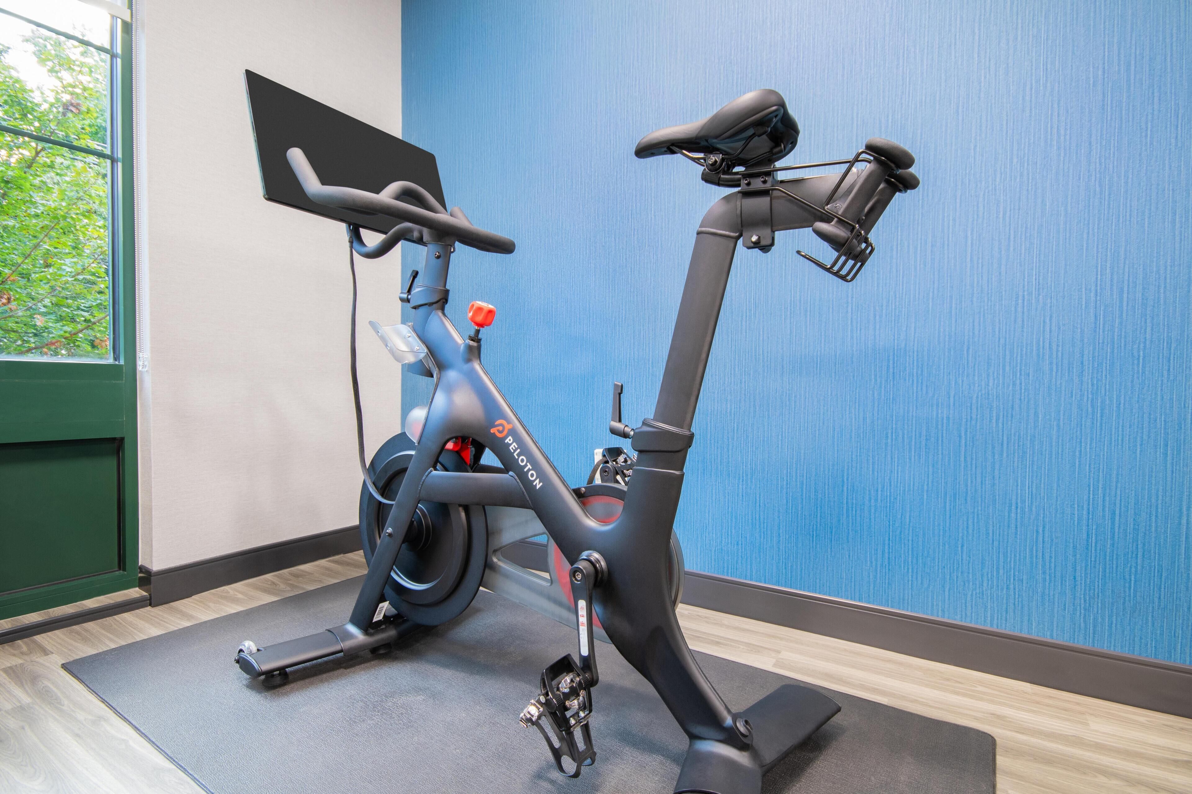 A stationary bike in a room with a blue wall and a window.