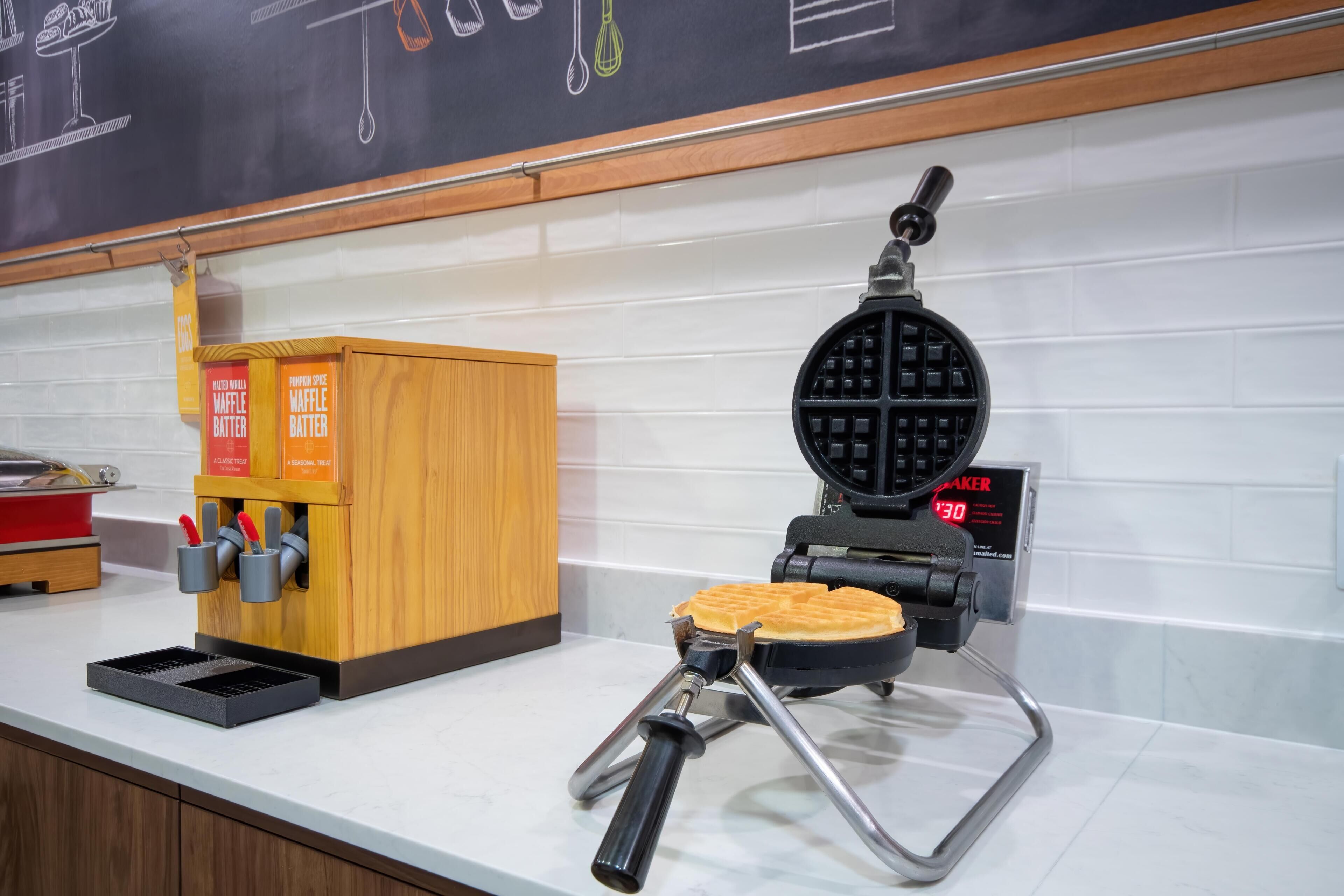 A waffle maker on a countertop with a waffle being cooked.