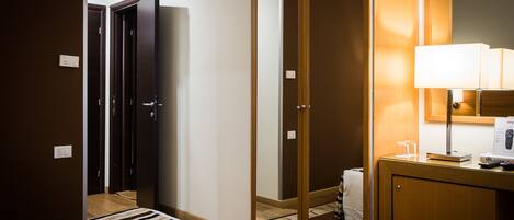 Une chambre d’hôtel comprenant un lit, une table de chevet avec une lampe, un miroir et une armoire.