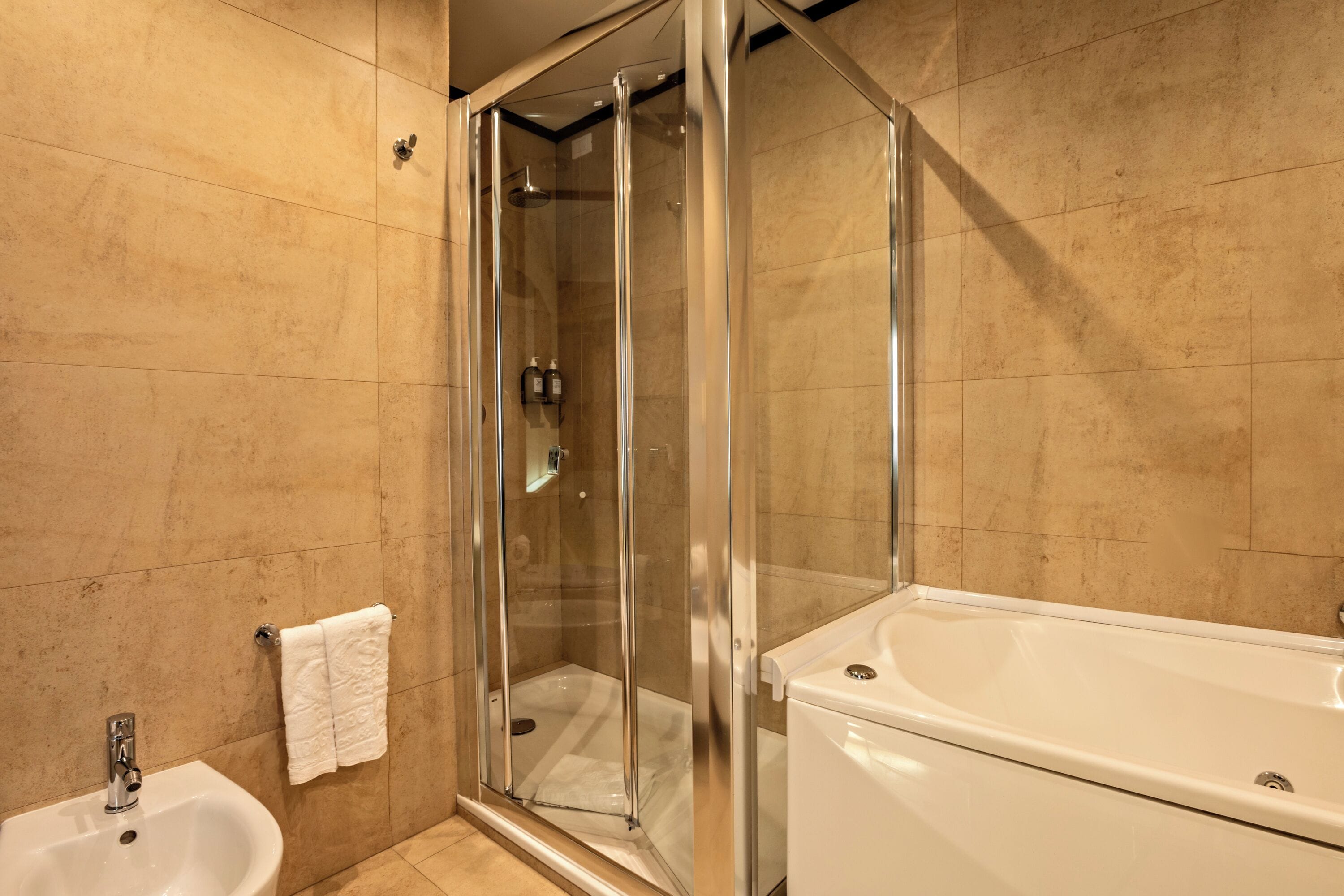A modern bathroom with a glass-enclosed shower, a white bathtub, and a sink.