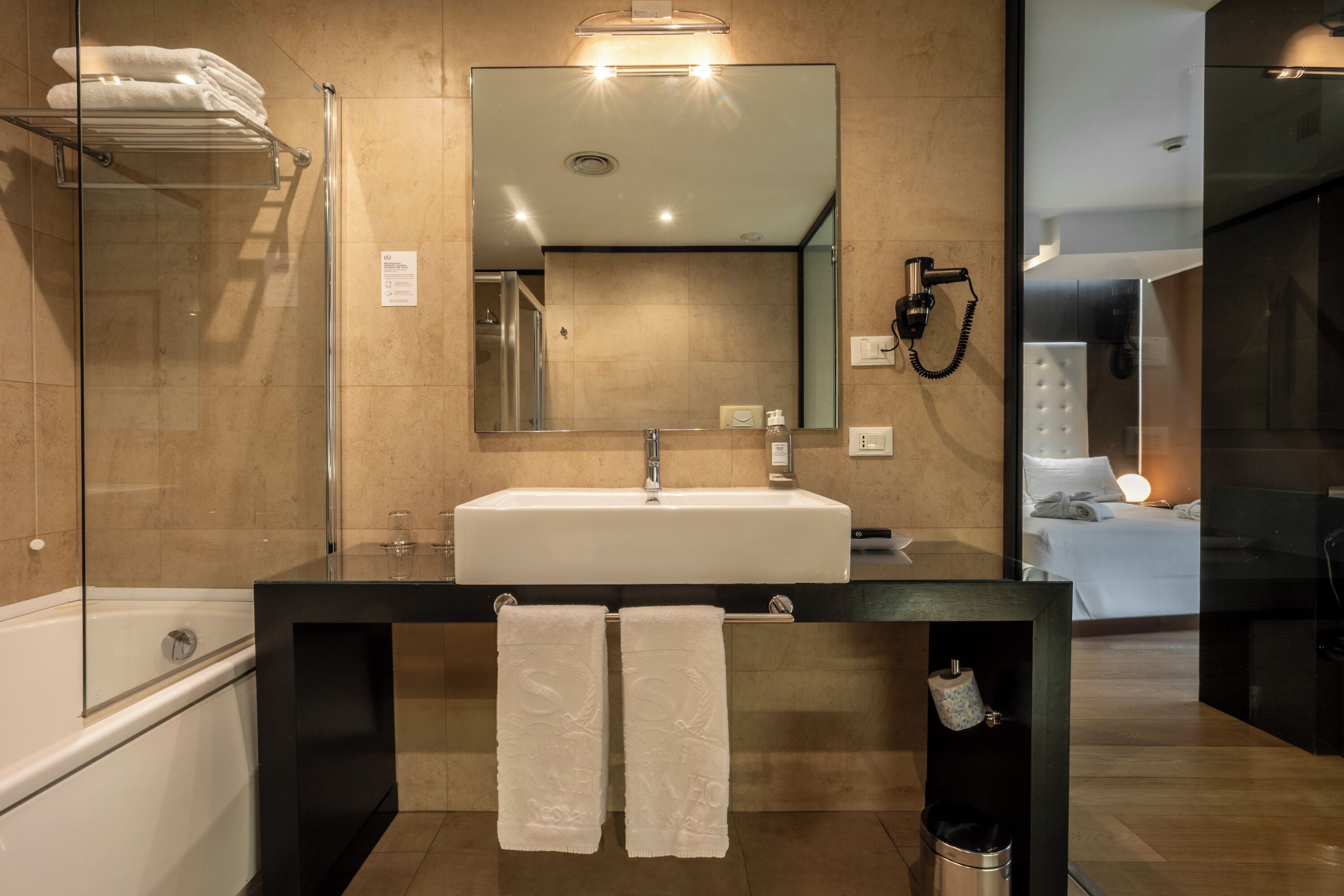 Une salle de bain moderne avec un grand miroir, un lavabo blanc et une douche à parois de verre.
