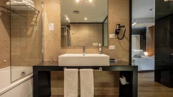 Une salle de bain moderne avec un grand miroir, un lavabo blanc et une douche à parois de verre.