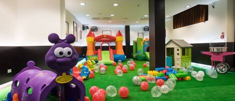 Un área de juegos infantiles con estructuras inflables, una piscina de pelotas y diversos juguetes.
