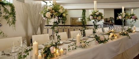 A long banquet table set with candles, glassware, and floral centerpieces.