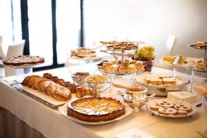 Una mesa de bufé con diversos pasteles, postres y frutas.