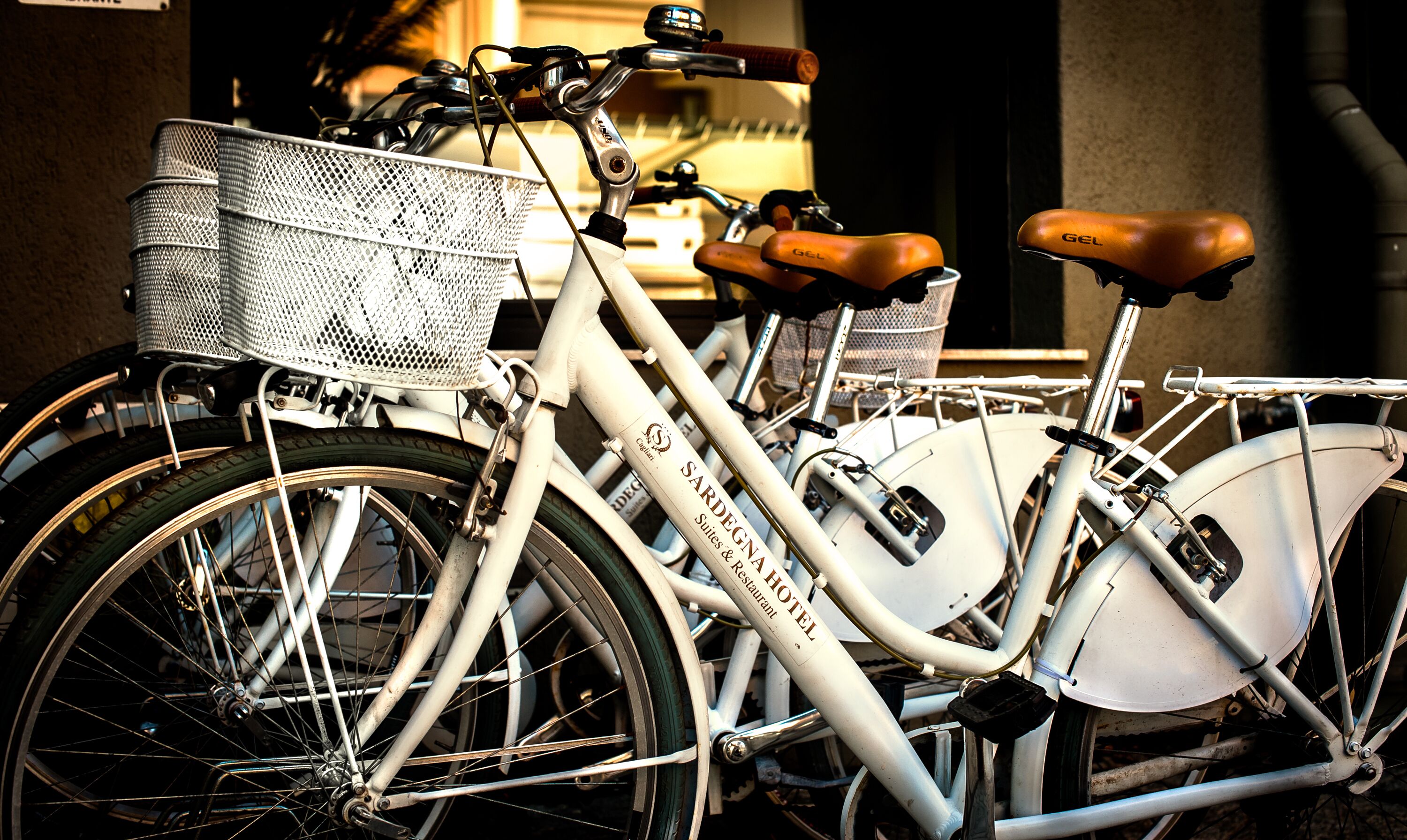 A bicycle with a basket and a seat, parked next to a building.