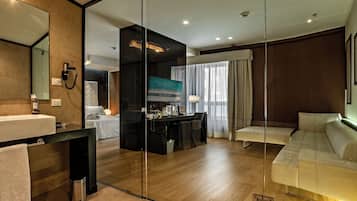 Une chambre d’hôtel moderne dotée d’un grand miroir, d’un bureau avec un téléviseur à écran plat, d’un canapé et d’une salle de bain séparée.