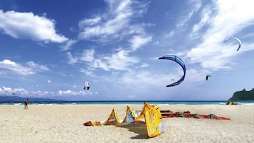 Ein Strand mit fliegenden Drachen am Himmel und einem Sandufer.
