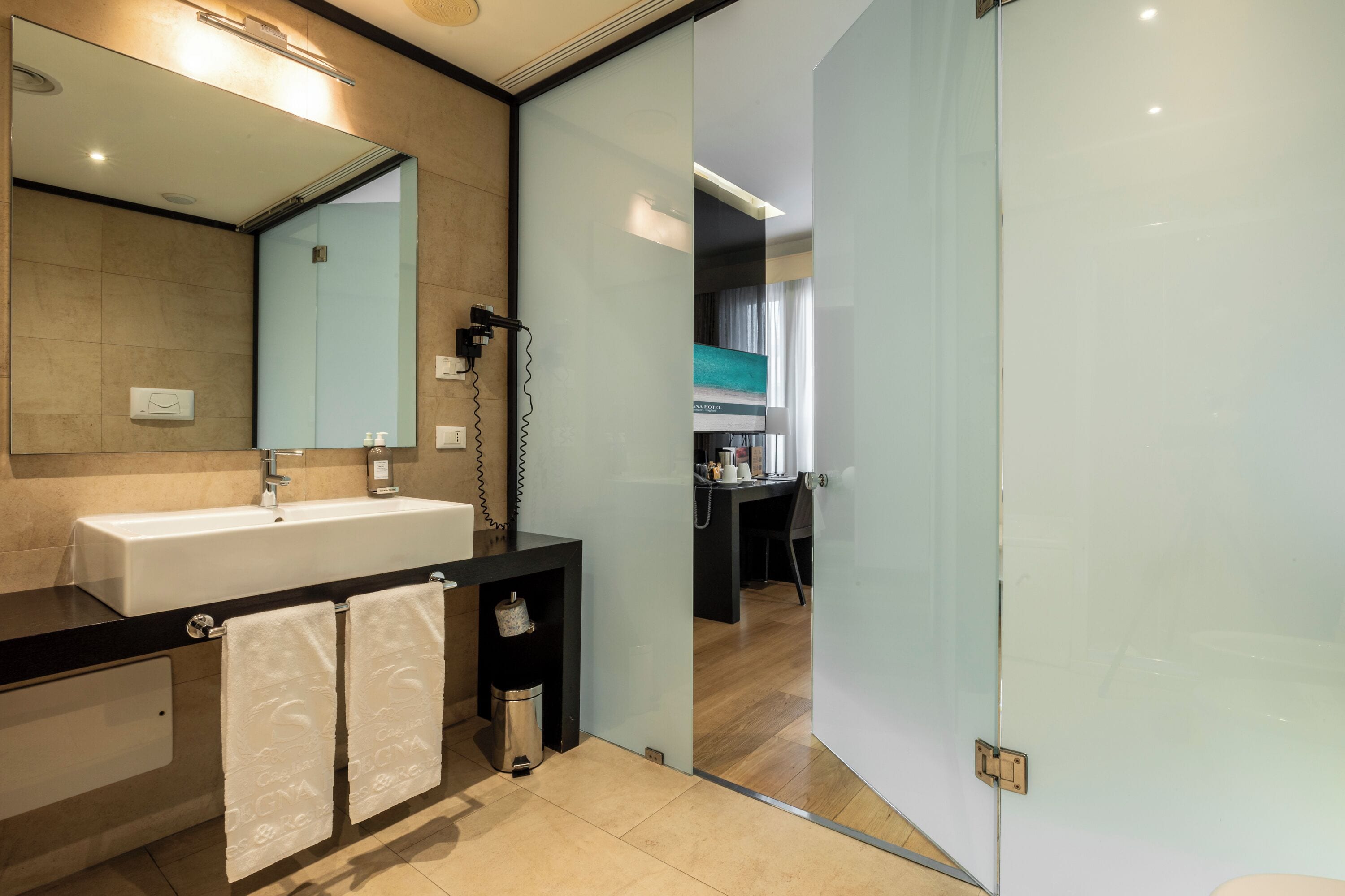 Un baño moderno con un espejo grande, un lavabo y una zona de ducha.
