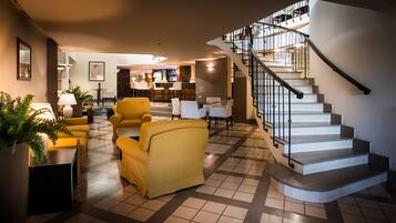 Eine Hotelhalle mit Treppe, Sitzgelegenheiten und einer Bar.