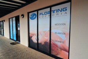 A building facade with large windows advertising Floating Euphoria, a wellness center offering meditation, relaxation, calmness, and relief services.