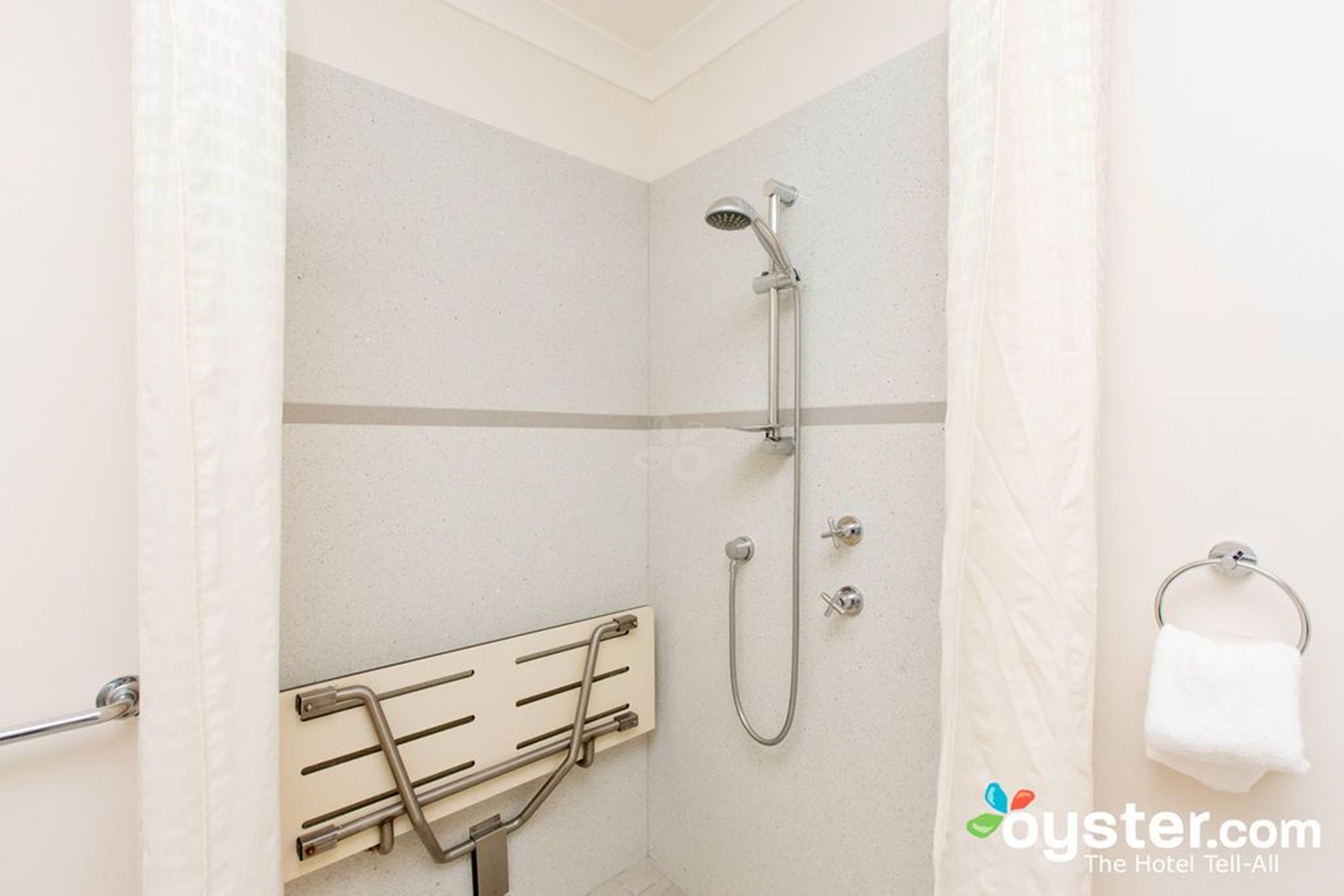 Een douche met een handdouche en een handdoekrek.
