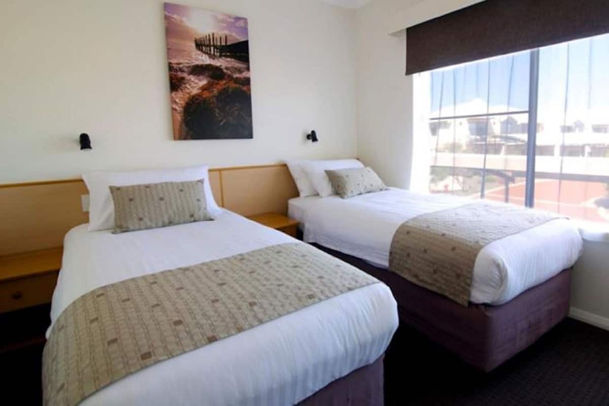 Ein Hotelzimmer mit zwei Betten, einem Fenster mit Blick und einem Bild an der Wand.