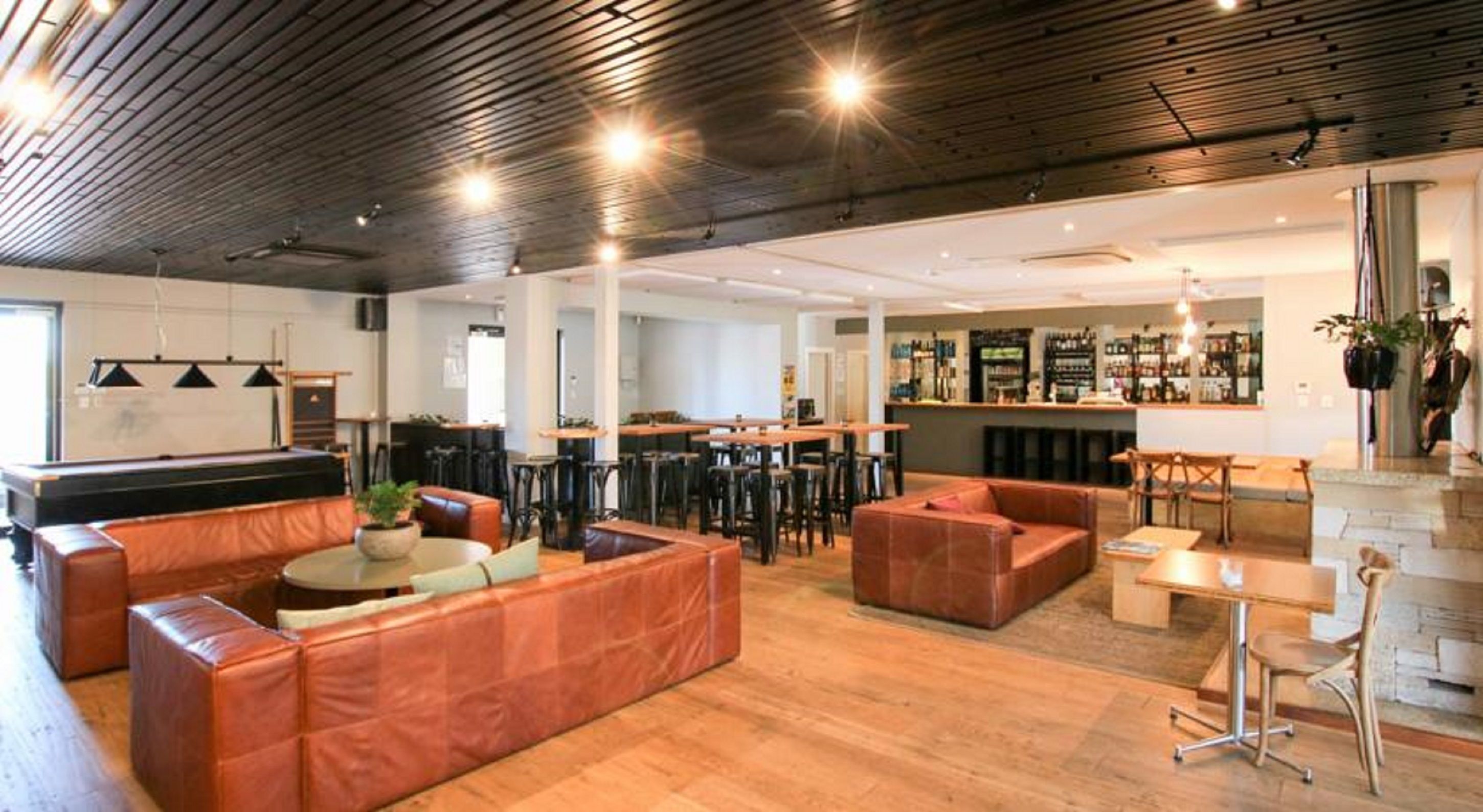 A spacious lounge area with leather seating, a bar, and a pool table.