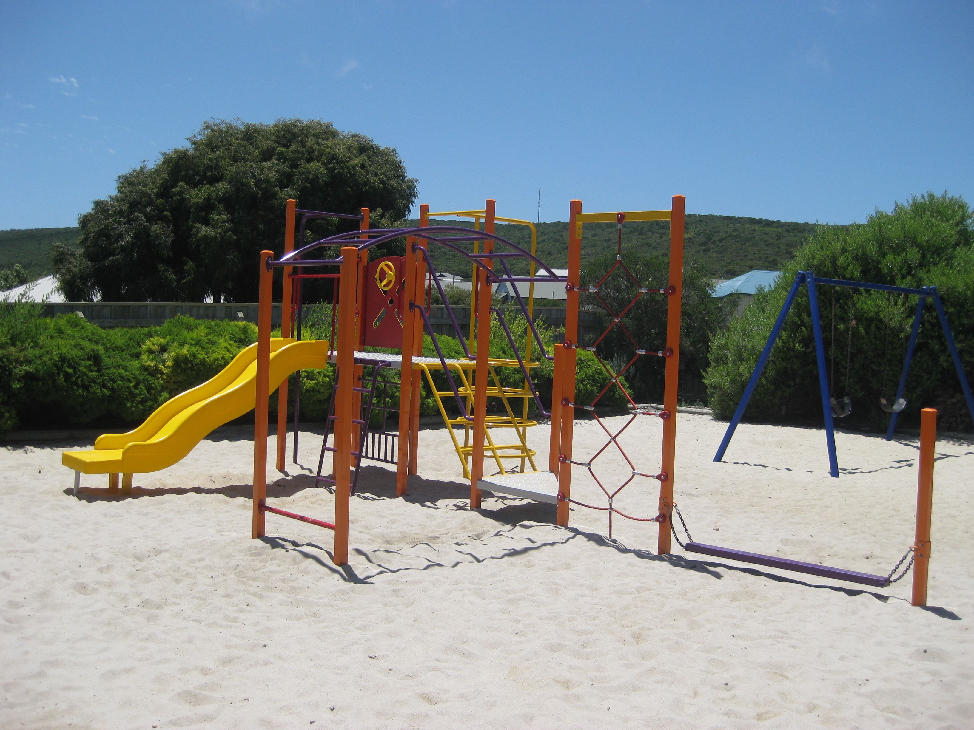 A playground with a yellow slide and climbing structures.
