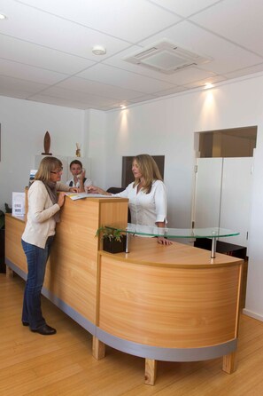 A reception desk in a modern office with a glass top, wooden paneling, and a sign offering free WiFi.