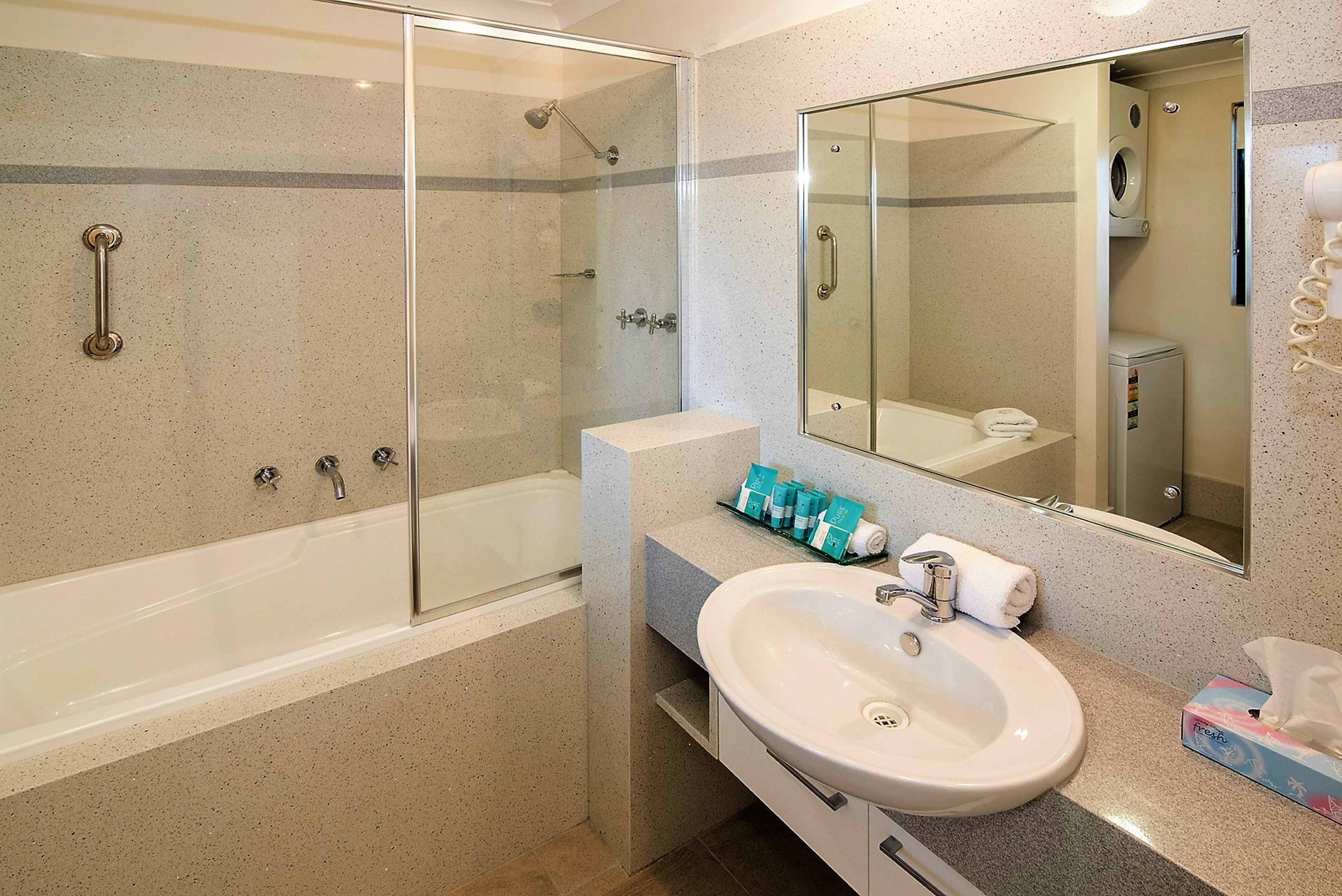 A bathroom with a glass-enclosed shower, a white sink, and a mirror above it.