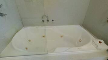 Una bañera rectangular estándar con puerta de vidrio, grifo y mando.