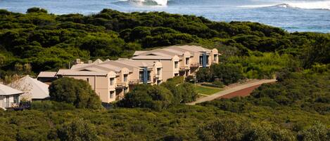 Un hotel costero con varias edificaciones, rodeado de abundante vegetación y el océano.