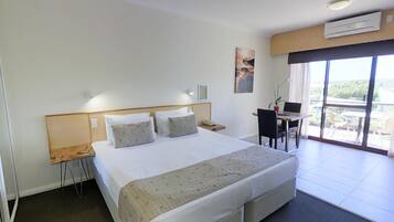 Een hotelkamer met een groot bed, een bureau met stoel en uitzicht op de omgeving.