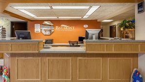 A hotel reception desk with a wooden finish, a Dell computer, and a sign for Baymont Inn & Suites. - Baymont by Wyndham Midland (Midland)