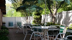 A patio with a table and chairs, surrounded by a white fence and trees. - Baymont by Wyndham Midland (Midland)