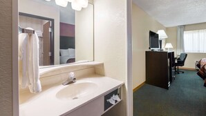 A hotel bathroom with a large mirror, a sink, and a towel rack. - Baymont by Wyndham Midland (Midland)