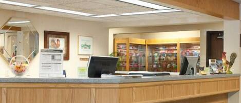 A reception area with a wooden counter, a computer, and a glass display case with items.