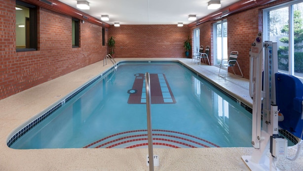 An indoor swimming pool with a clear lane divider, a lifeguard chair, and a pool lift on the right side. - Baymont by Wyndham Midland (Midland)