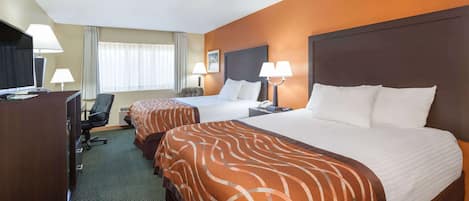 A hotel room with two beds, a desk, and a chair.