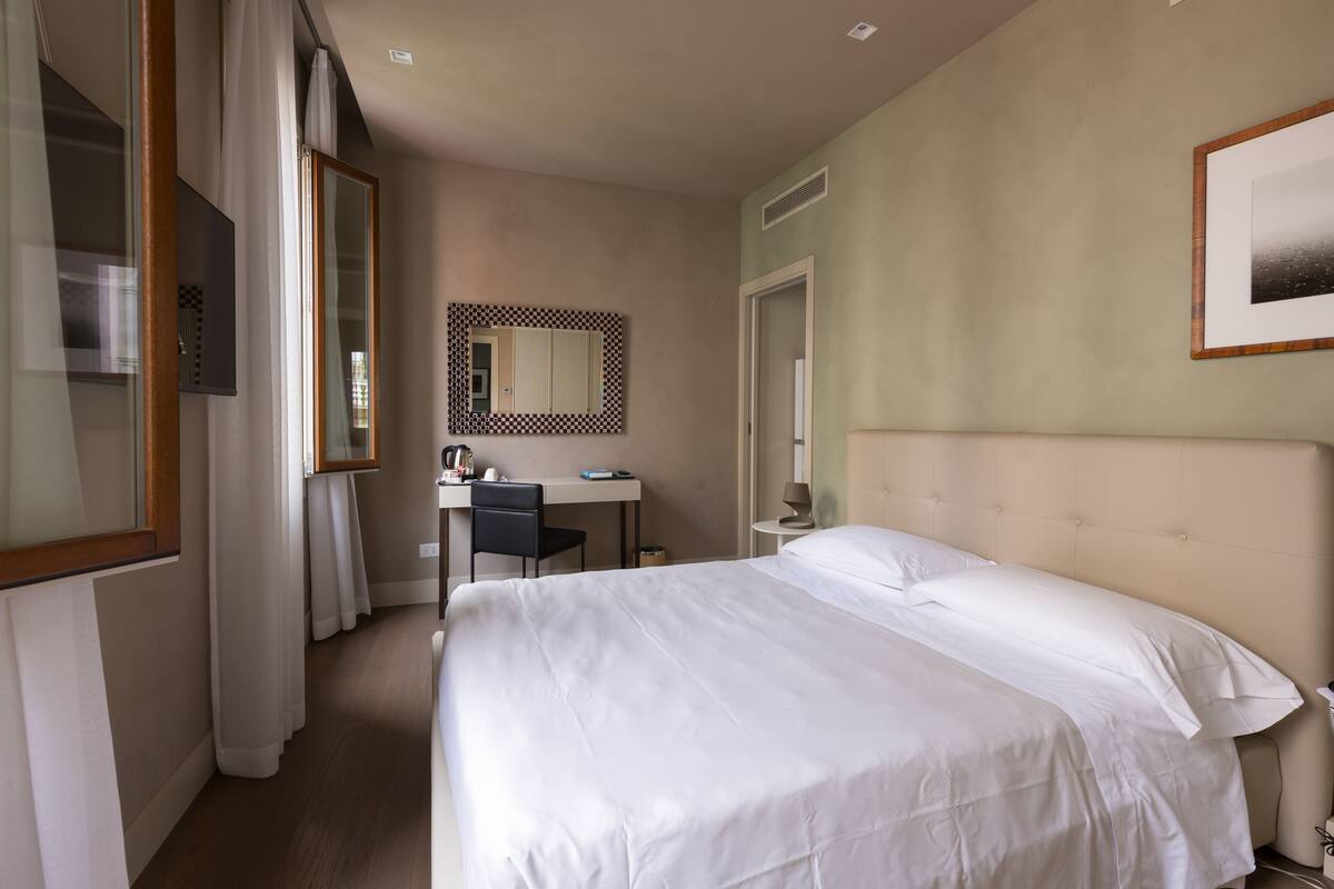 Ein Hotelzimmer mit einem großen Bett, einem Schreibtisch, einem Stuhl und einem Spiegel.
