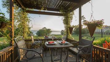 An outdoor patio with wicker chairs and tables, overlooking a golf course and a body of water.