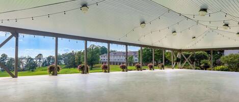 An indoor space with a high ceiling, large windows, and a view of a building and greenery outside.