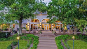 A large, two-story building with a central courtyard, surrounded by lush greenery and a well-maintained garden. - Cypress Bend Resort, a Wyndham Hotel (Many)