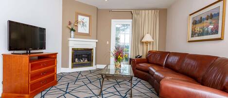 A living room with a television, a fireplace, a sofa, and a patterned carpet.