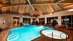 An indoor swimming pool with a wooden ceiling, clear glass walls, and a seating area with chairs and potted plants. - Cypress Bend Resort, a Wyndham Hotel (Many)