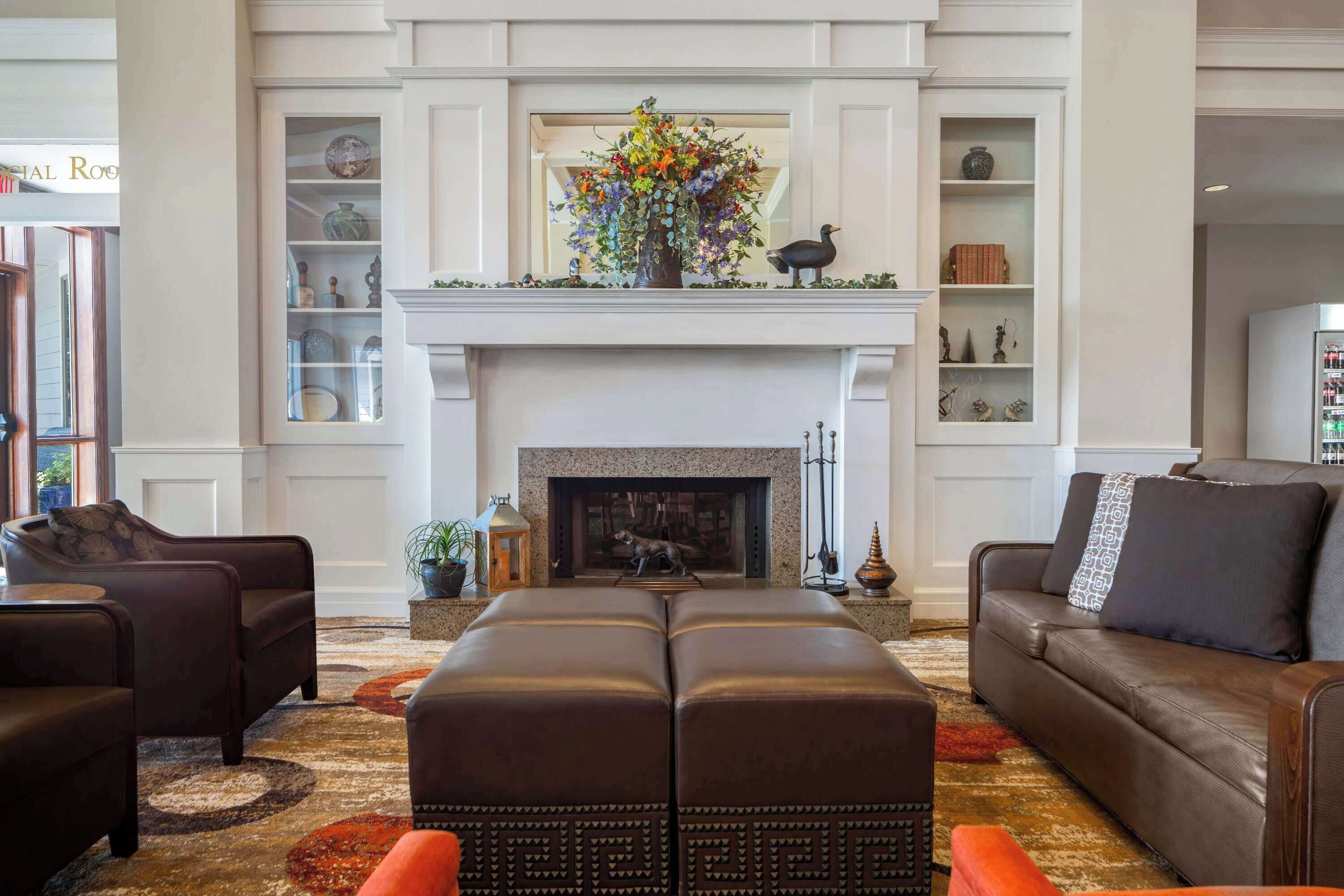 A living room with a fireplace, leather sofas, and a decorative mantelpiece.