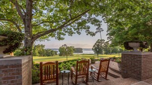 A patio with two wooden chairs and a small table, overlooking a golf course and a body of water. - Cypress Bend Resort, a Wyndham Hotel (Many)