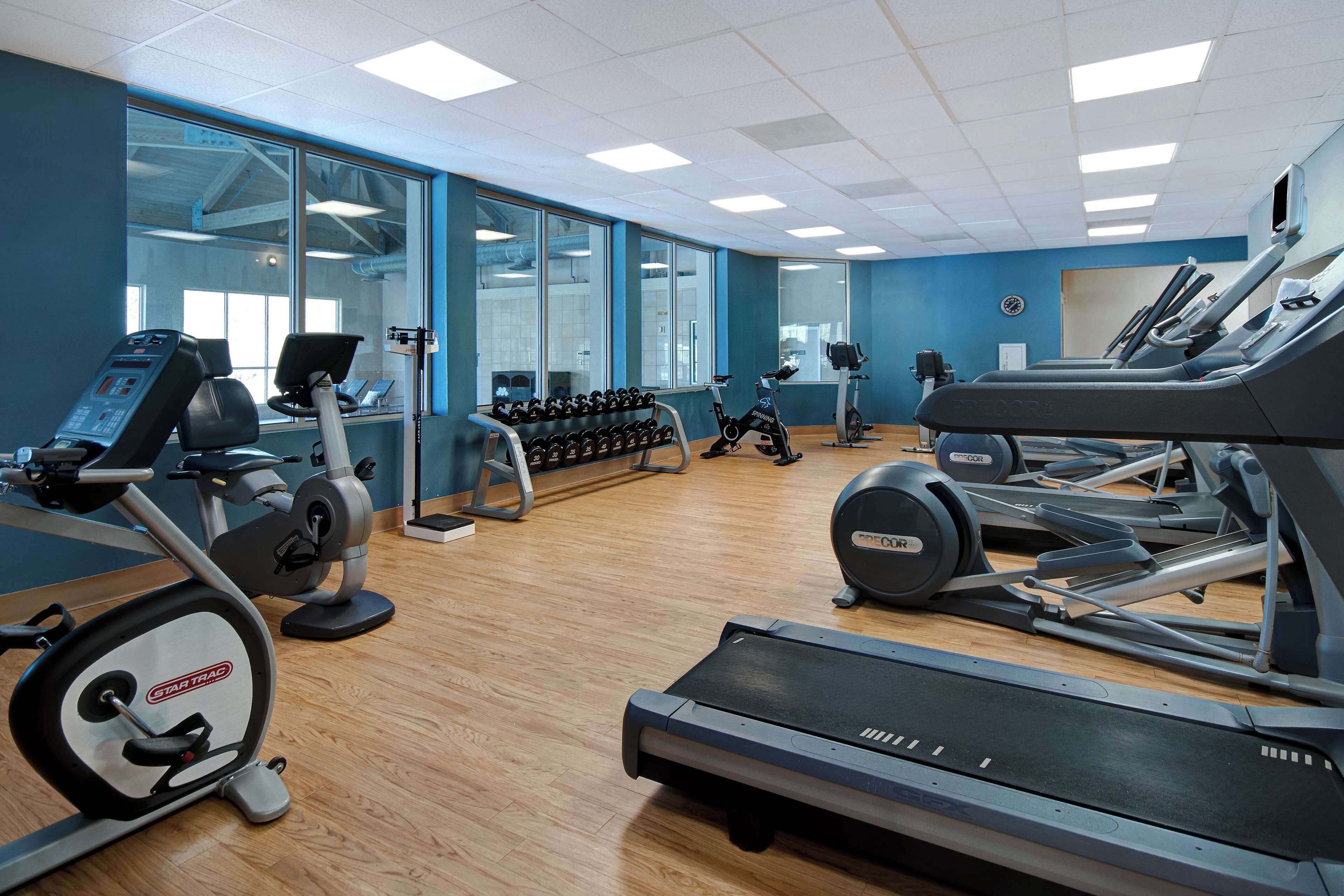 Une salle de sport équipée de machines de cardio, d’haltères et d’un miroir.