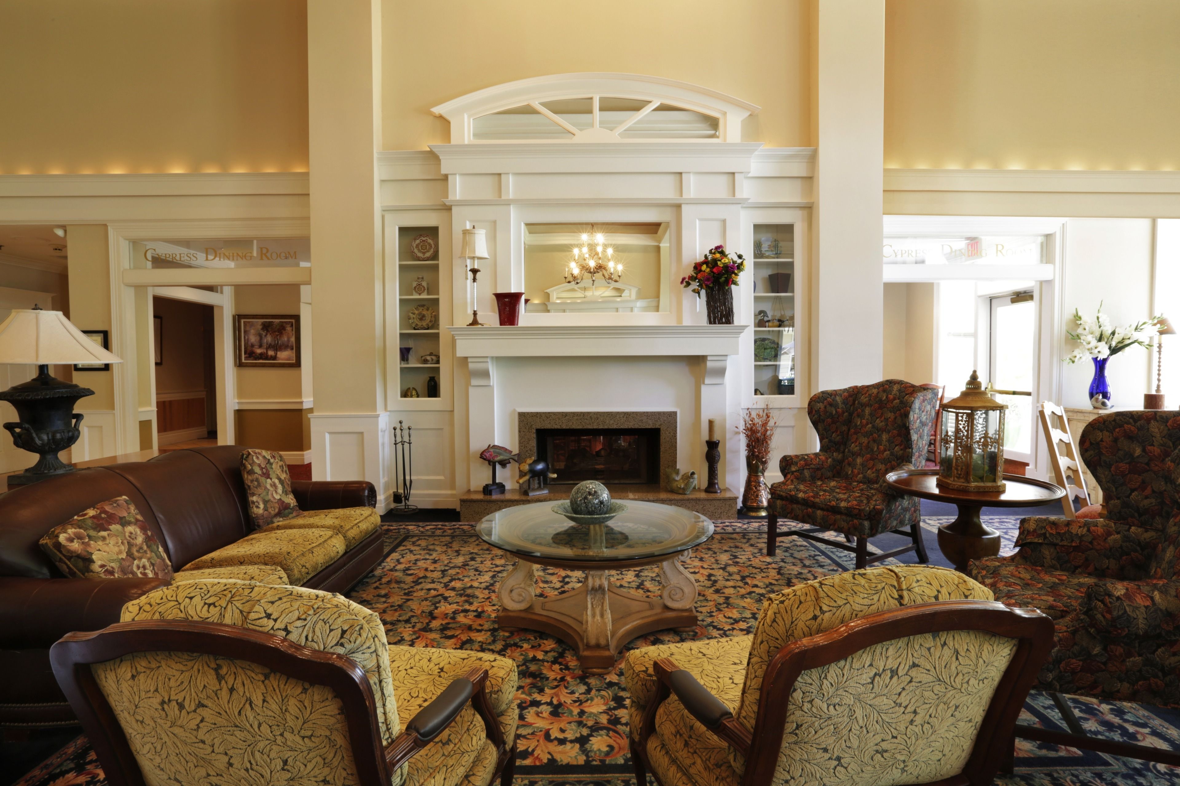 A spacious living room with a fireplace, comfortable seating, and a chandelier.