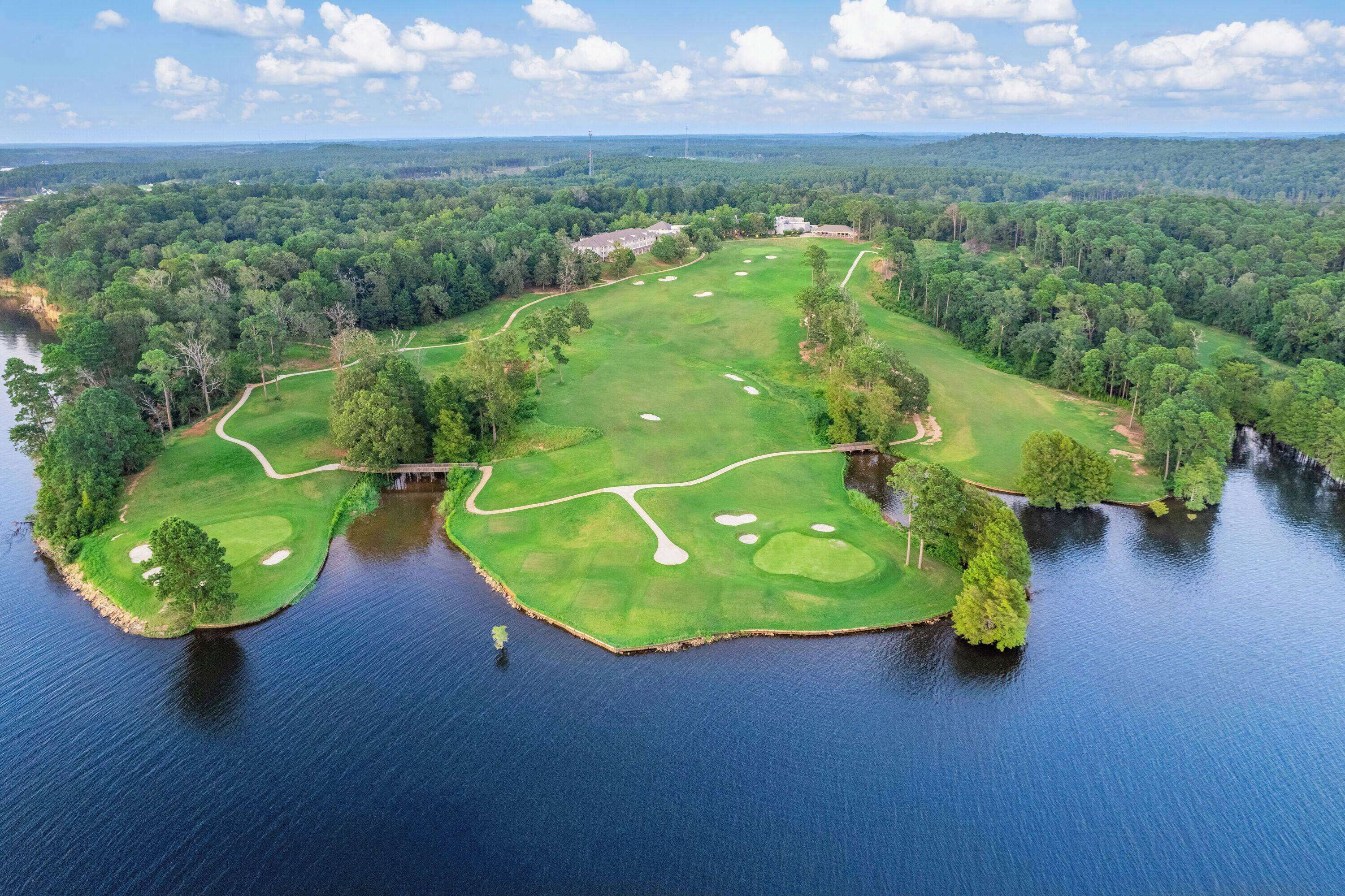 A golf course with water bodies and forested areas.