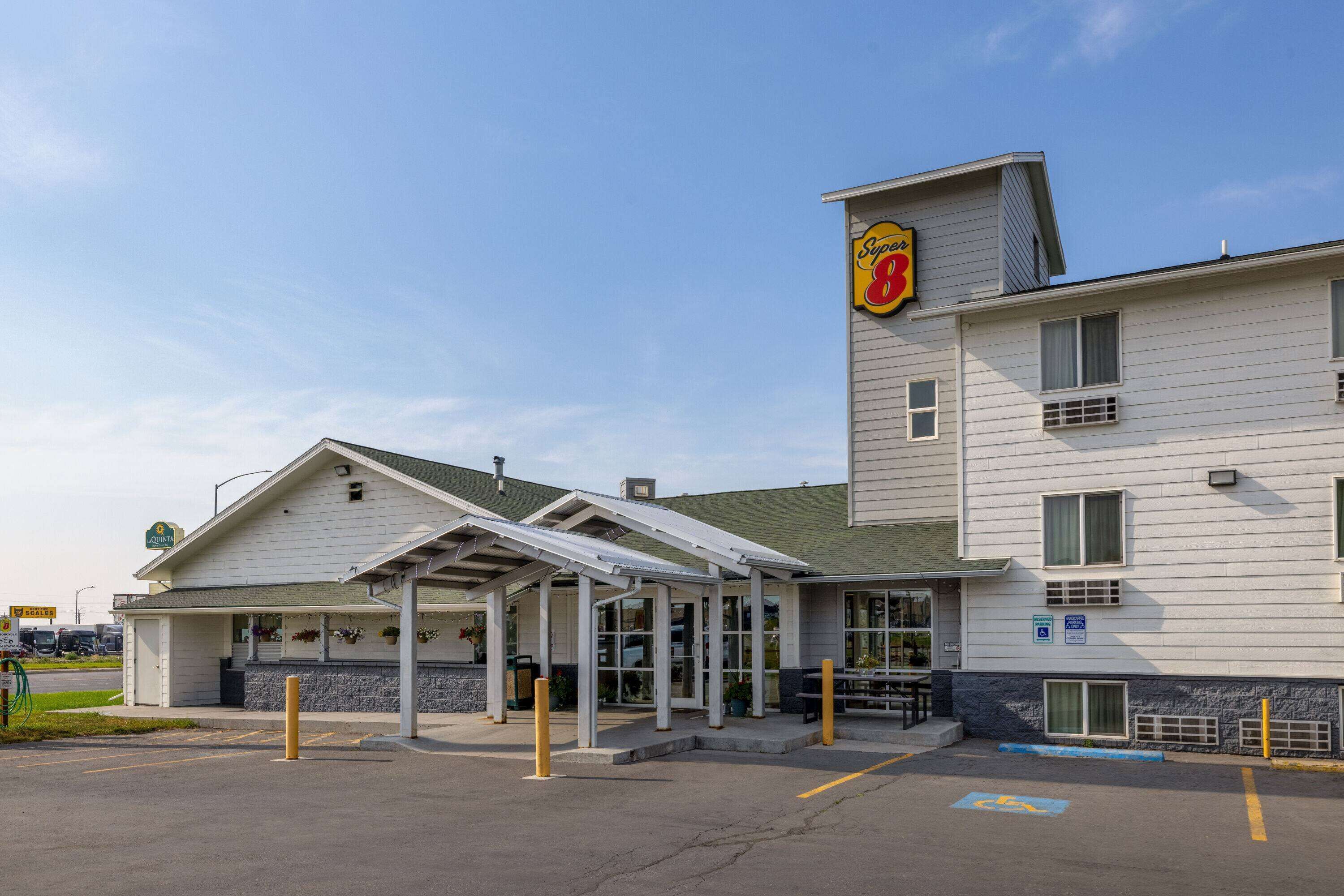 Ein Motel mit überdachtem Parkplatz, einem Schild mit der Aufschrift Super 8 und einem Stellplatz für Menschen mit Behinderung.