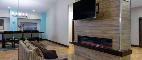 Una sala de estar moderna con chimenea, un televisor de pantalla plana y un comedor con candelabro.