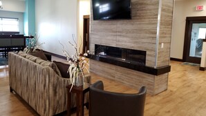 A modern lobby with a sofa, a flat-screen TV, and a fireplace.