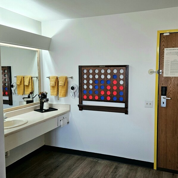 Un baño con lavabo, espejo, toallero y un juego GoSports fijado a la pared.