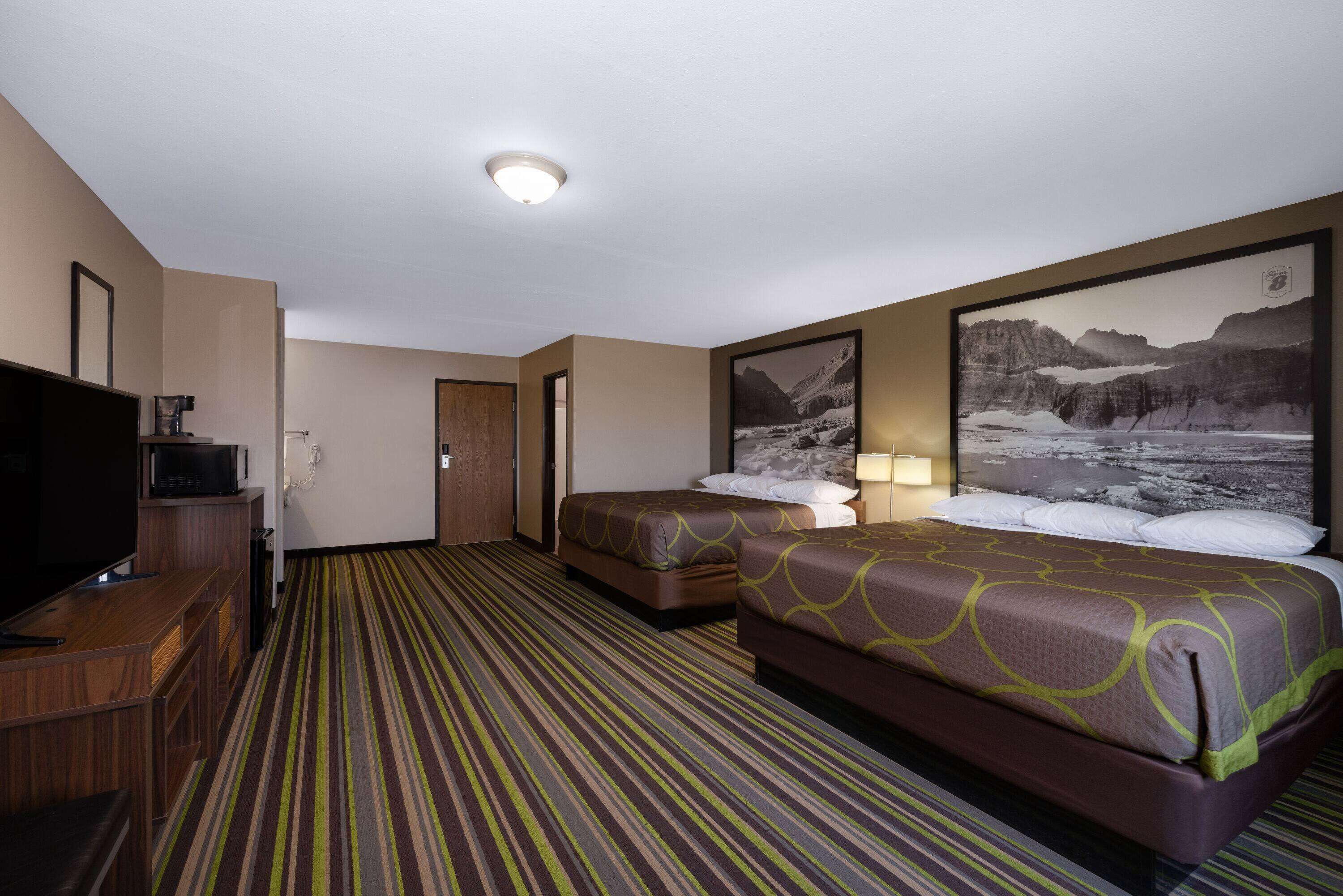 A hotel room with two beds, a TV, and a large framed picture on the wall.